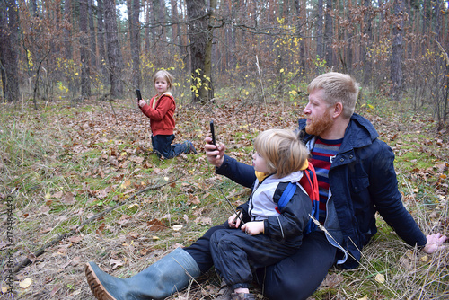A father and children are taking a picture of the landscape in the forest.