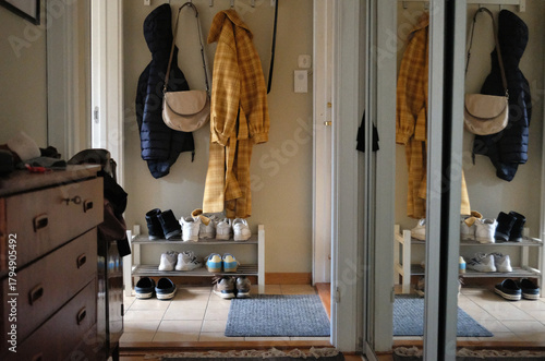 entrance part of the apartment, with outer clothes hanging and a shoes on a rack	