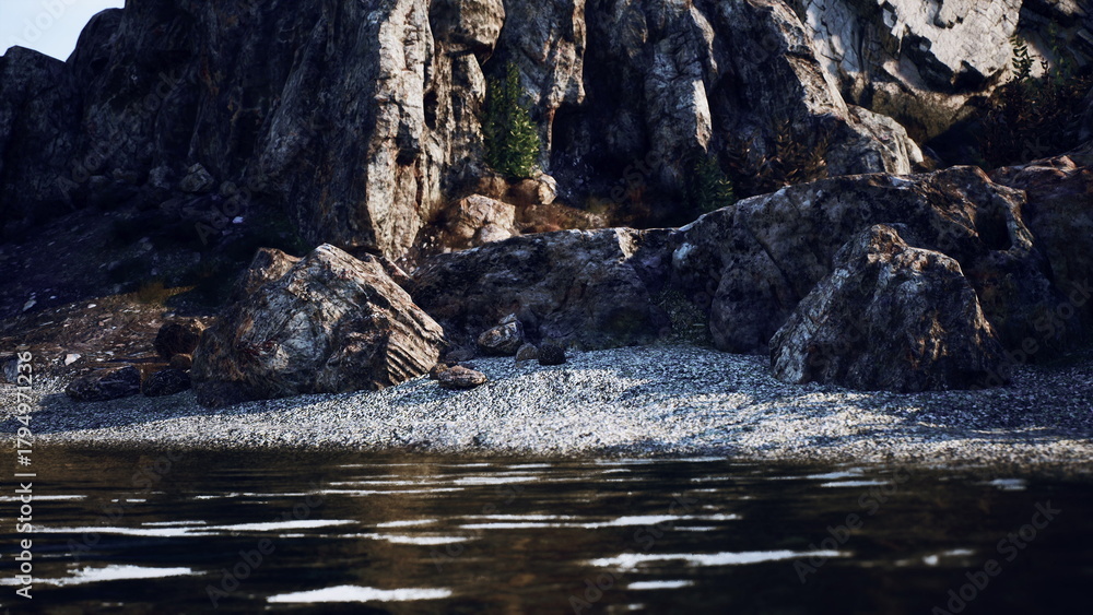 Obraz premium Waves gently lap against the pebbly beach as towering rocks stand majestically nearby. Soft sunlight highlights intricate textures on the shore, creating a peaceful atmosphere.