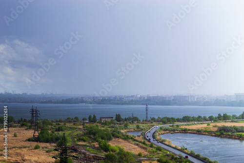 Rainstorm over lake and industrial cityscape