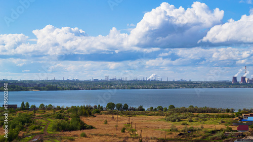 Power plant by lake under bright beautiful clouds
