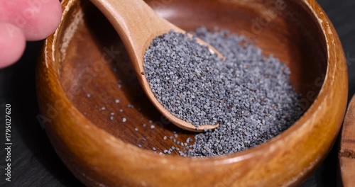 poppy seeds in a wooden bowl used in the manufacture of confectionery, a large amount of poppy seeds in a wooden bowl with a spoon