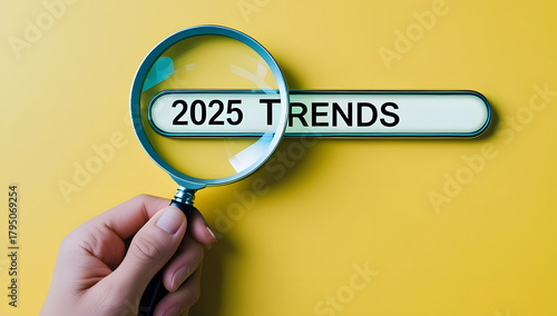 Magnifying glass searching for current 'trends' on a vibrant yellow background
