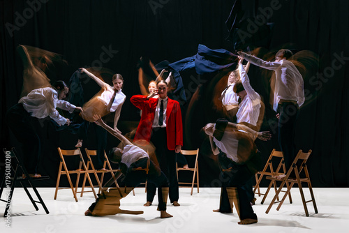 Ensemble with motion-blur performing expressive movements around still central figure in red jacket. Concept of emotional theatre, expressive movement language, dynamics and artistic storytelling.