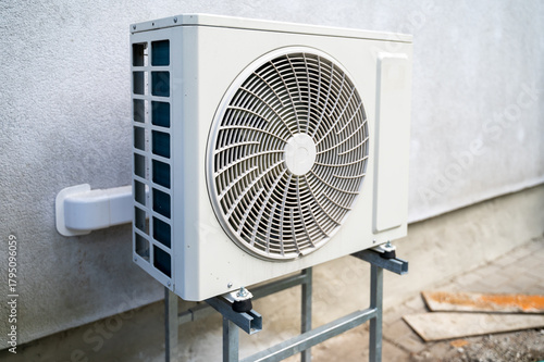 Outdoor air conditioning unit stands in backyard of private house