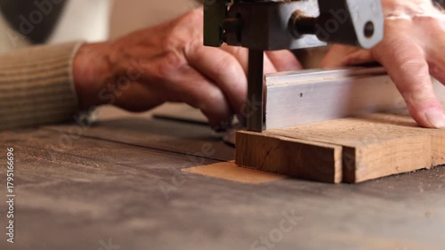 Un menuisier en train d'utiliser une scie à ruban pour découper une planche dans son atelier.