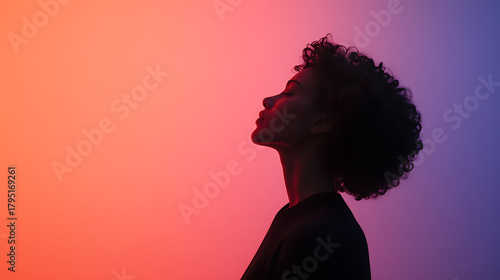 Silhouette of a woman with curly hair against a vibrant gradient background. Her face is tilted up, exuding serenity and peace. The lighting creates a strong contrast and focuses on her features.