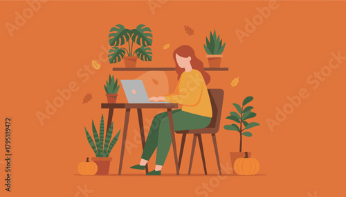 Woman remote working on laptop in a cozy autumn home office with plants and pumpkins
