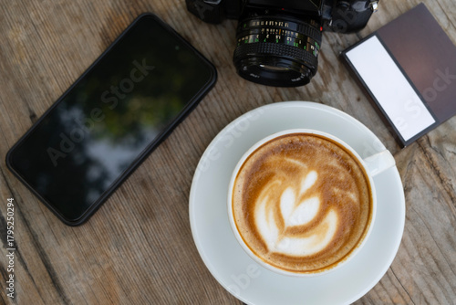 Creative workspace with coffee, camera, and phone. Latte coffee with camera and smartphone on wooden table. Coffee break with camera and mobile phone.