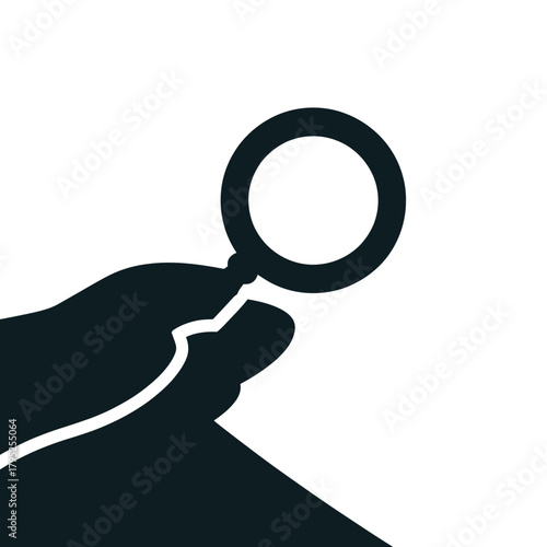 Silhouette of a hand holding a magnifying glass over a surface