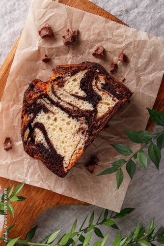 slice of marble cake with chocolate swirl on parchment paper, rustic dessert, wooden background