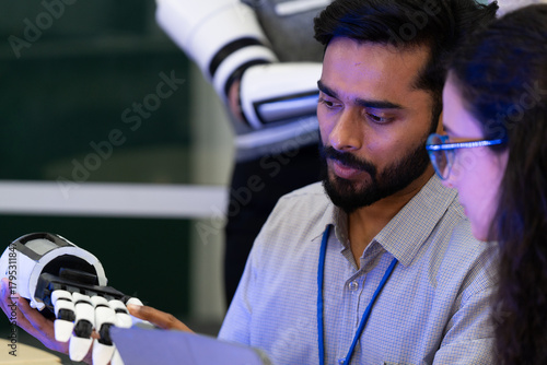 Engineer demonstrating advanced robotic prosthetic arm technology with colleague in research lab. Concept of innovation, artificial intelligence, robotics, human-machine collaboration, and healthcare.