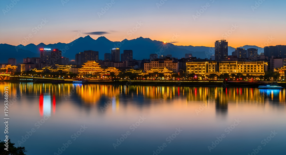 Fototapeta premium City skyline reflected in water at dusk with mountain backdrop