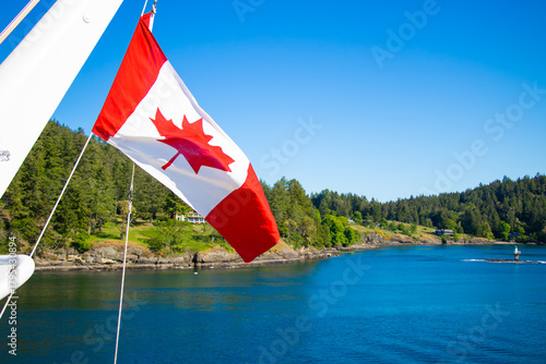 Canadian Flag Waving Above the Forest Coastline of Galiano and Mayne Islands, British Columbia
