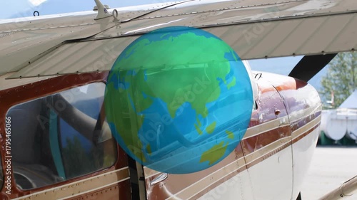 Plane cockpit with pilot leaning and reaching while globe appearing and rotating to show navigation