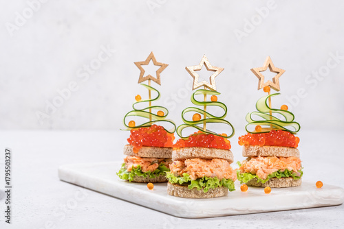 Holiday canapes shaped like Christmas trees with smoked salmon and vibrant toppings for festive gatherings