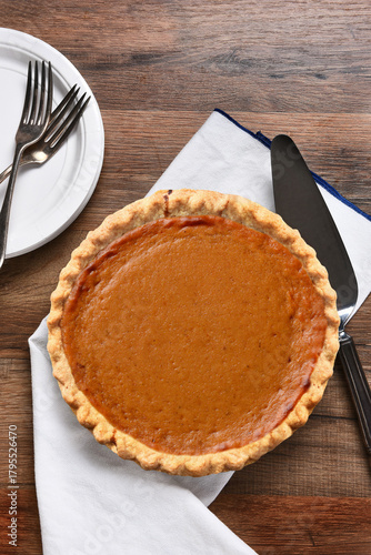 A fresh baked Pumpkin pie with server, plates and forks. The dessert is part of a typical Thanksgiving Day Feast.