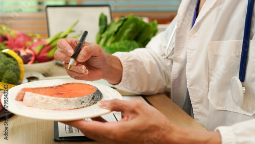 Male dietitian sitting at desk with different healthy products and writing diet plan, Healthy life style concept, doctor writing, diet and losing weight