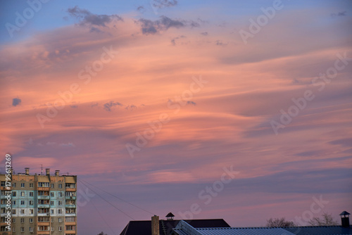 Lenticular round clouds over houses in the city at sunset