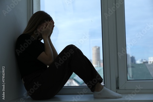 Depressed teenage girl near window at home Free Download Depressed teenage girl near window at home - GFXLoad
