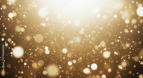 Golden glittering particles and bokeh on dark background.