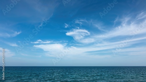 Vast ocean under a blue sky with wispy clouds. Nature scene, peaceful and serene. The sea and sky, natural landscape.