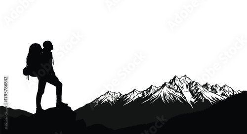 Hiker silhouette on rocky outcrop overlooking snowy mountains