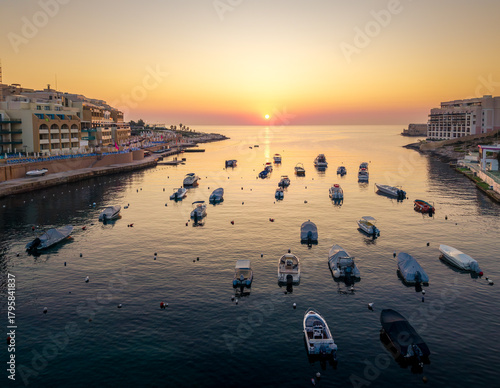 Beautiful sunset over calm waters in Paceville, Malta with boats at rest