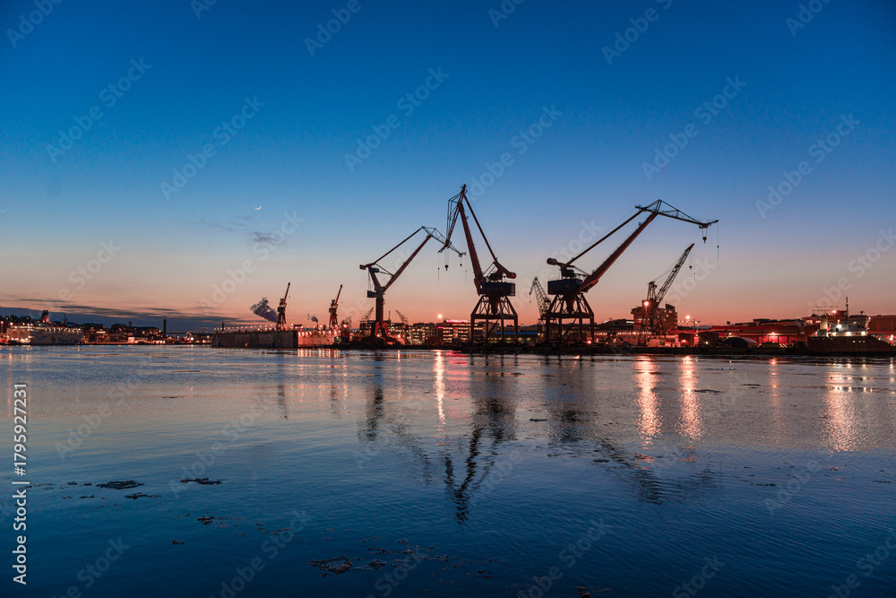 Fototapeta premium Industrial harbor cranes reflecting in evening water.