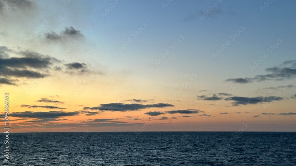 Naklejka premium Soft pastel ocean sunset with glowing horizon and scattered clouds