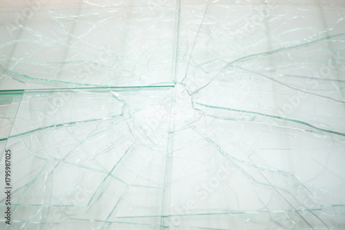 Nahaufnahme einer zerbrochenen Glasscheibe, helle Lichtreflexe, feine Risse und Bruchlinien, abstrakt, keine weiteren Objekte sichtbar.
