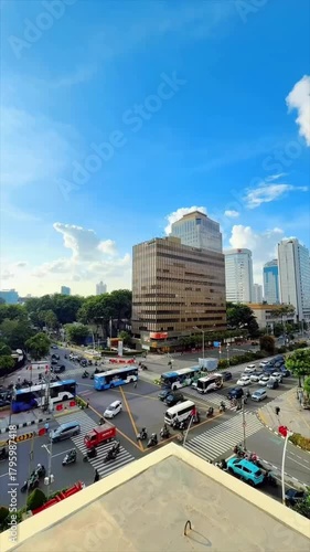 video portrait of heavy traffic at a red light in the middle of the city with a background of buildings and clear skies