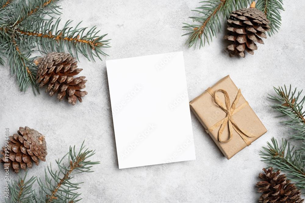 Fototapeta premium Happy New Year greeting card mockup with gift box and Christmas tree branches with cones, flat lay with copy space