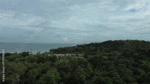 Expansive drone panorama reveals verdant coastal hills meeting tranquil azure waters beneath a