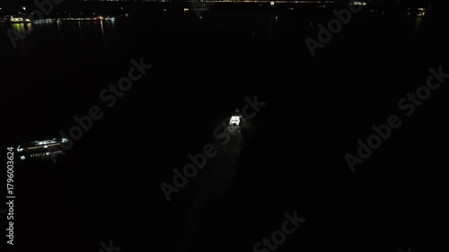Nighttime Aerial Odyssey Over Tranquil Waters with City Lights and Serene Boat Journeys