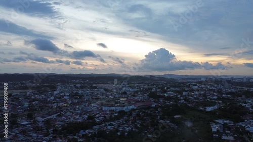 Panoramic aerial video of a tropical city at dusk, capturing the sprawling urban essence below.
