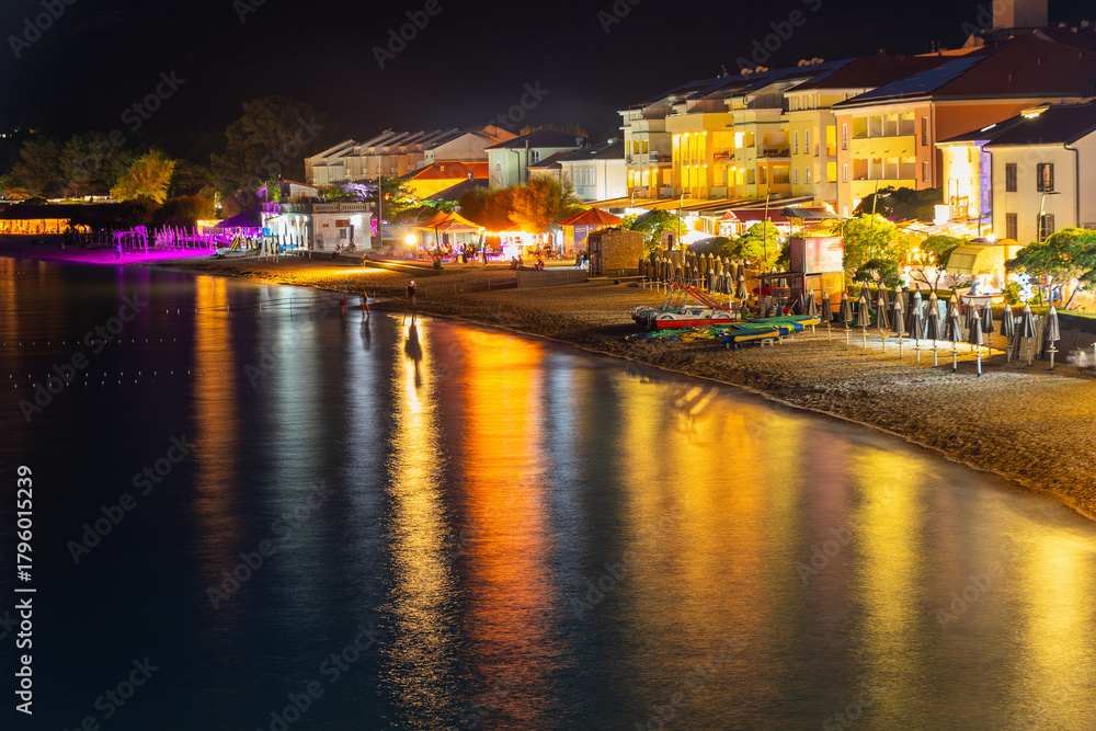 Fototapeta premium Colorful night view of illuminated seaside promenade and beachfront buildings. Baška, Krk island, Croatia