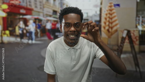 Foto Young african american man smiling makes roaring hand gesture on a colorful bustling city street; playful spirit