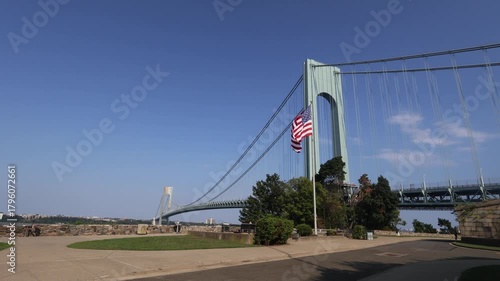 american flag waving in front of the verrazzano bridge in staten island new york (cars passing on highway) usa america fort historical site traffic narrows hudson river waterfront suspension cables