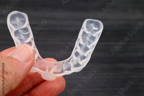 歯の矯正用のマウスピースを持つ人物のクローズアップ