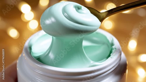 Jar of cream with spoon on golden background. Light green cream and golden spoon