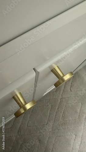Quadro em tela Gold metal cabinet pulls on white cabinetry above textured bathroom rug