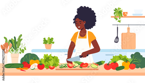 Smiling African American woman in an apron chopping fresh colorful vegetables on a cutting board to prepare a healthy salad in her kitchen
