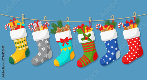 Festive Christmas stockings filled with gifts, candy canes, and holiday treats hanging on a string against a blue background