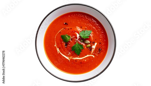 Overhead shot of a bowl filled with smooth, vibrant red soup, garnished with herbs, cream swirl, seeds, and black specks