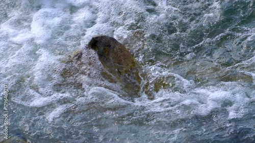 Slow motion water flowing over a large rock