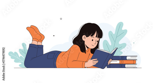 A young woman lies comfortably on her stomach, engrossed in reading a book, with a stack of books beside her.