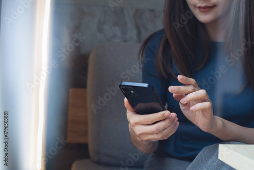 Close up, Young asian woman using mobile phone for online shopping, digital banking and social network via social media app. Casual business woman surfing the internet at cafe