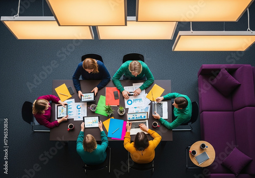 Top view of a diverse team collaborating around a table with laptops and documents during a meeting
