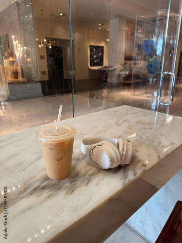 Iced Coffee and Wireless Headphones on Marble Table in Modern Café